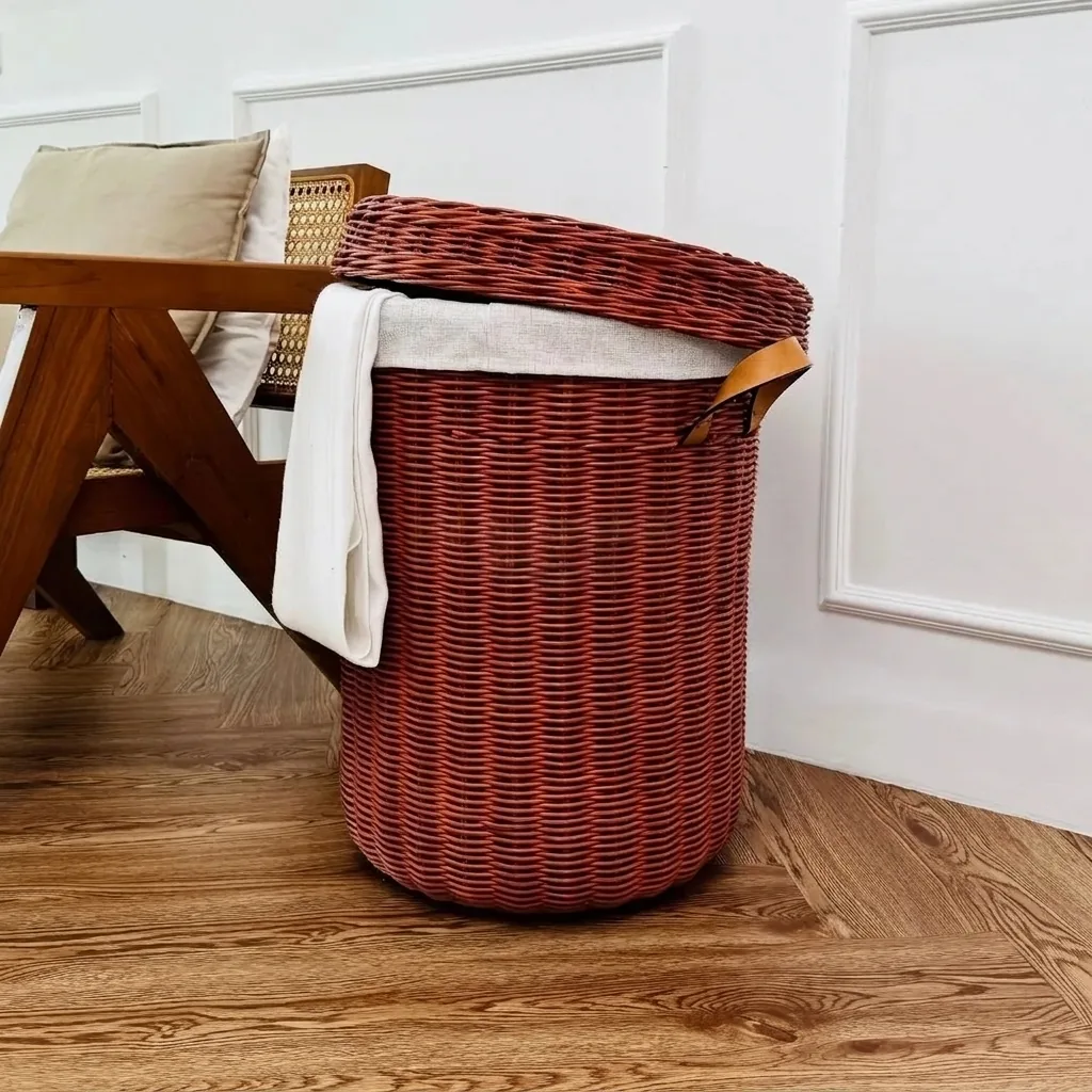Burgundy-coloured rattan hamper with white fabric lining and leather handles